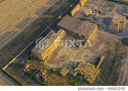 Large farming compound full of large heaps of hay bales. Large farming compound full of large heaps of hay bales. 64063249