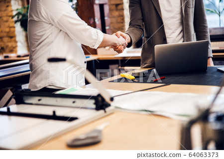 Business partners are shaking hands in office 64063373