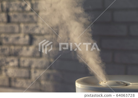 Humidifier spreading steam with white brick wall 64063728