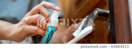 woman hand disinfecting the door handle by 64064813