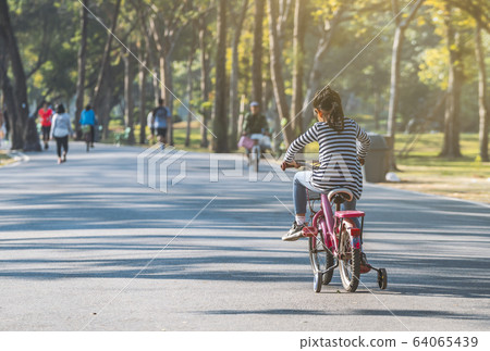 Child girl practicing biking bicycle Child girl practicing biking bicycle 64065439