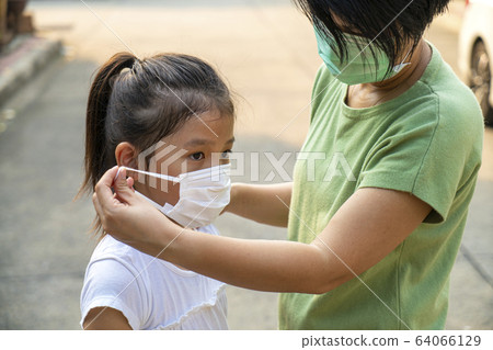 Chinese mother helping her daughter wearing pm 2.5 mask 64066129