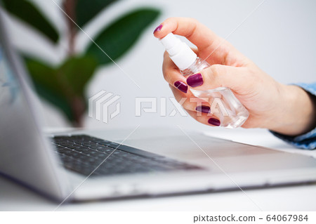 Woman in office uses antiseptic for disinfection Woman in office uses antiseptic for disinfection 64067984