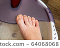 Step-by-step pedicure at home. Pedicure at home, soaking your feet in a special foot massage bath. Photo of a senior women's feet in an electric foot spa 64068068