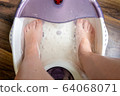 Step-by-step pedicure at home. Pedicure at home, soaking your feet in a special foot massage bath. Photo of a senior women's feet in an electric foot spa 64068071