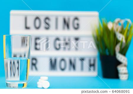 Glass of water and pill for weight loss 64068091