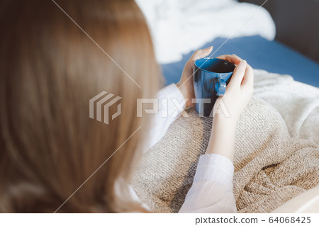 warm coffee in blue cup in young beautiful asian woman hand during relax in cozy room at her home warm coffee in blue cup in young beautiful asian woman hand during relax in cozy room at her home 64068425