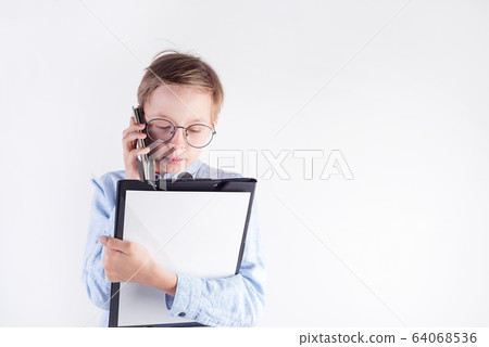 Young boy in glasses and mockup paper clipboard in his hand is on the phone against light grey background. Young boy in glasses and mockup paper clipboard in his hand is on the phone against light grey background. 64068536