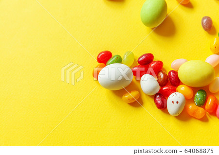 Happy Easter concept. Preparation for holiday. Easter candy chocolate eggs and jellybean sweets isolated on trendy yellow background. Simple minimalism flat lay top view copy space. 64068875
