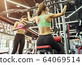 Young sport woman working out with trainer in gym. 64069514