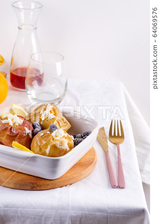 Baked apples with blueberries and cottage cheese in bowl with cutlery on white table Baked apples with blueberries and cottage cheese in bowl with cutlery on white table 64069576