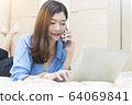 Businesswoman using mobile and laptop on bed. Free 64069841