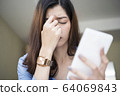 Young woman using smartphone tired rubbing nose 64069843
