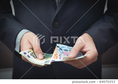 Man in a suit counts Euro banknotes 64070353