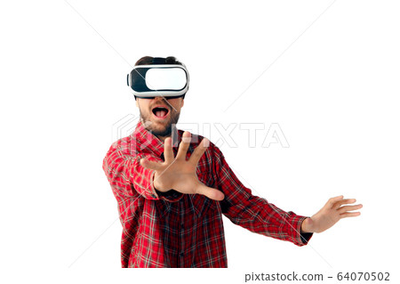 Man emotional playing, using virtual reality headset isolated on white studio background Man emotional playing, using virtual reality headset isolated on white studio background 64070502