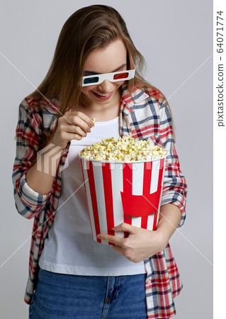 beautiful young woman eating popcorn from bucket beautiful young woman eating popcorn from bucket 64071774