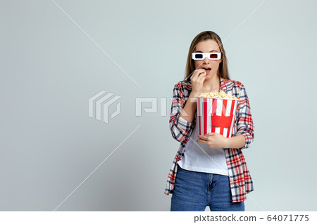 beautiful young woman eating popcorn from bucket 64071775
