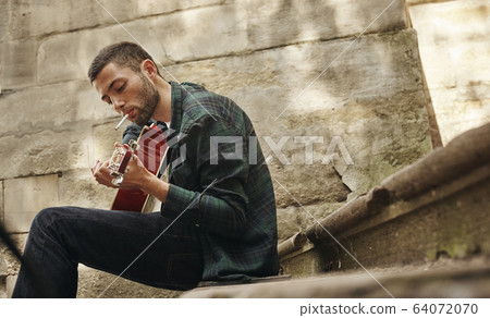 Lovely young street musician with guitar 64072070