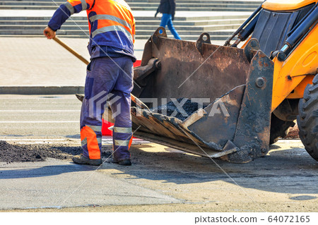 Partial repair of the asphalt road. A worker pours 64072165