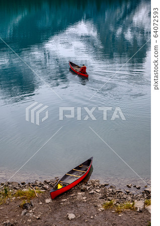 Traveler canoeing with red canoe parked on Maligne 64072593