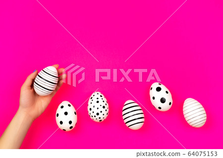 Different graphic hand-painted eggs on bright pink background. 64075153