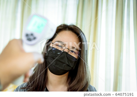Woman wearing mask protection flu with thermoscan 64075191