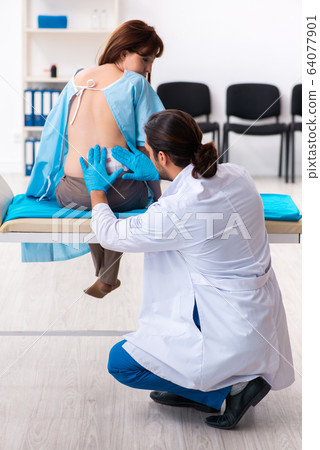 Injured young woman visiting young male doctor 64077901