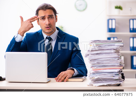 Young male employee unhappy with excessive work Young male employee unhappy with excessive work 64077975