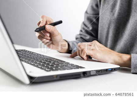 Designer sitting at desk and working at laptop Designer sitting at desk and working at laptop 64078561