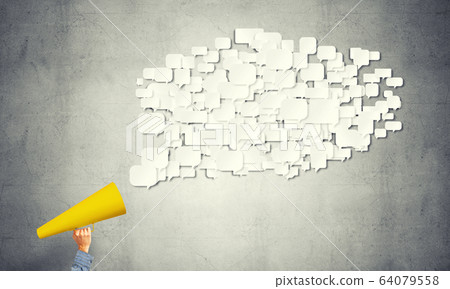 Hand of man holding yellow paper trumpet against concrete background 64079558