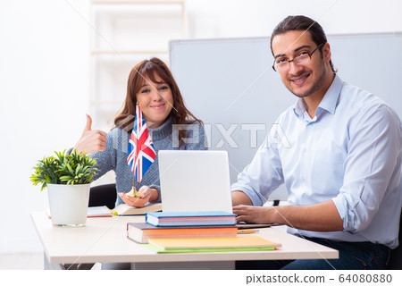 Young female student and male english teacher in the classroom 64080880