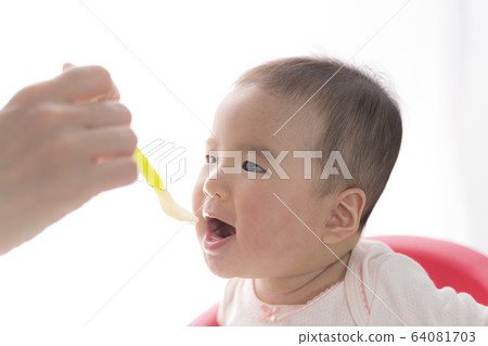 Baby eating baby food 64081703