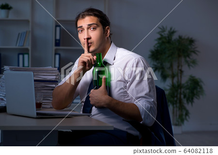 Alcohol addicted businessman working late in the office Alcohol addicted businessman working late in the office 64082118