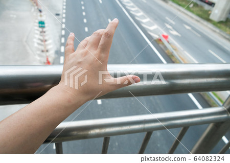 Hand touching footbridge railing 64082324