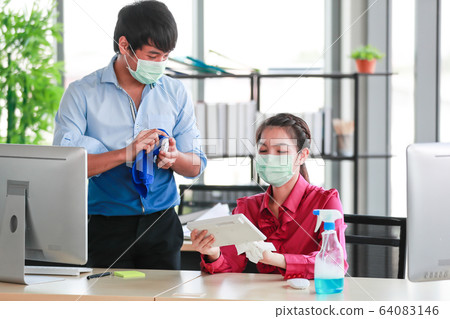 Employee disinfecting office equipment. 64083146