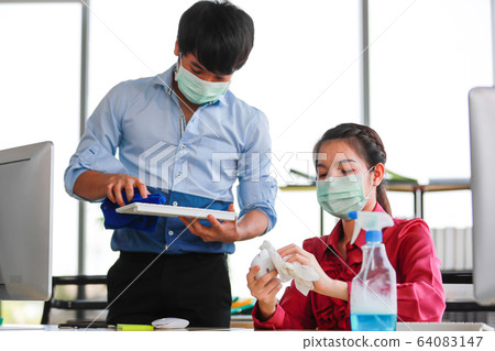 Employee disinfecting office equipment. Employee disinfecting office equipment. 64083147