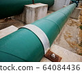 Metal clamp with green plumbing pipe bolts on the cement platform On a cement floor background. Selective focus 64084436