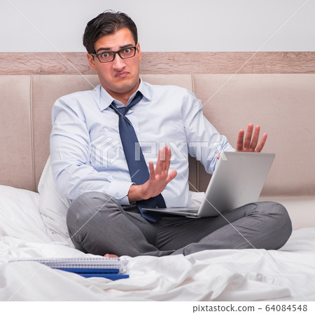 Businessman working in the bed at home Businessman working in the bed at home 64084548
