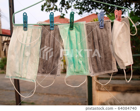Dry mask Many masks for protection against Covid-19 were washed and hung for drying. To reuse it again because the mask was in short supply or expensive during the crisis. Selective focus 64084740