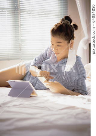 woman with protection mask in hand lying on sofa 64084850