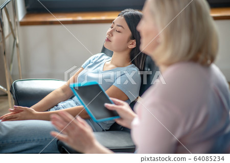 Blonde middle-aged psychiatrist working with a female patient 64085234