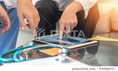 COVID-19 and doctor teamwork diagnosing lung infection disease on x-ray in digital tablet  64086057