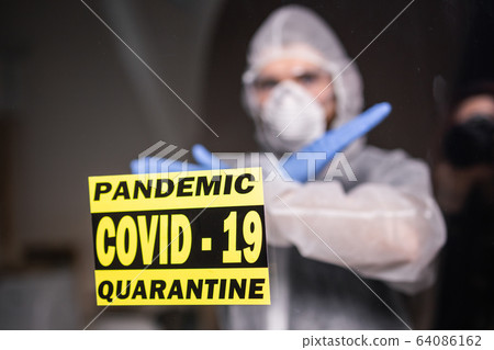 Man in protective white overalls, mask and glasses on his face. Coronavirus, pandemic, covid-19, flu and quarantine concept. 64086162
