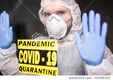 Man in protective white overalls, mask and glasses on his face. Coronavirus, pandemic, covid-19, flu and quarantine concept. Man in protective white overalls, mask and glasses on his face. Coronavirus, pandemic, covid-19, flu and quarantine concept. 64086165