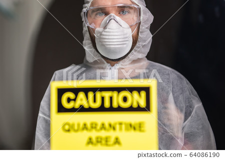 Man in protective white overalls, mask and glasses on his face. Coronavirus, pandemic, covid-19, flu and quarantine concept. 64086190