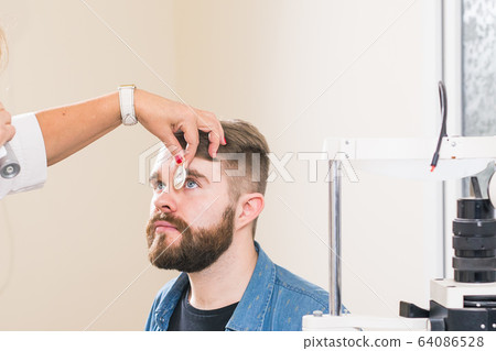 Medicine, health, ophthalmology concept - Ophthalmologist examines patient's eyes. Medicine, health, ophthalmology concept - Ophthalmologist examines patient's eyes. 64086528