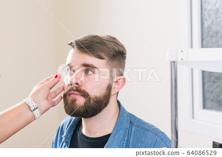 Medicine, health, ophthalmology concept - Ophthalmologist examines patient's eyes. 64086529