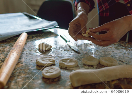 Woman cooking pies, also known as somsa, at home, making food from dough  64086619