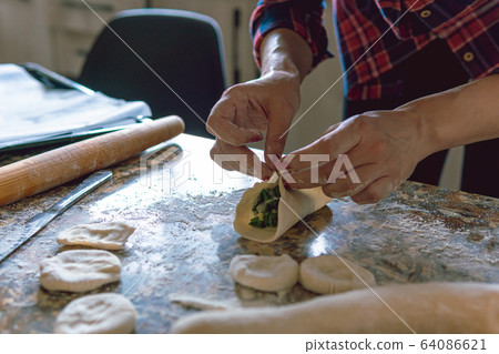 Woman cooking pies, also known as somsa, at home, making food from dough  64086621