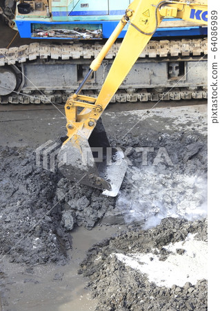Construction site: Power shovel that mixes ground improvement materials 64086989